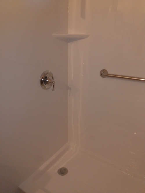Faucet and shelf at the front of the shower stall